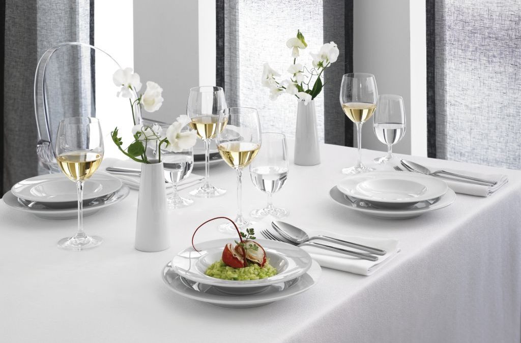 Weingläser und weißes Porzellan auf weiß gedecktem Tisch